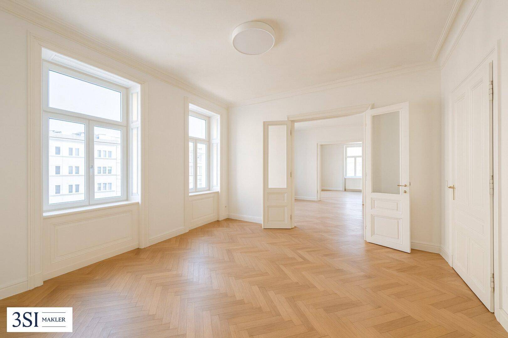 Geräumiges, helles Zimmer mit Fischgrätparkett und hohen Türen, ideal für Wohnzwecke.