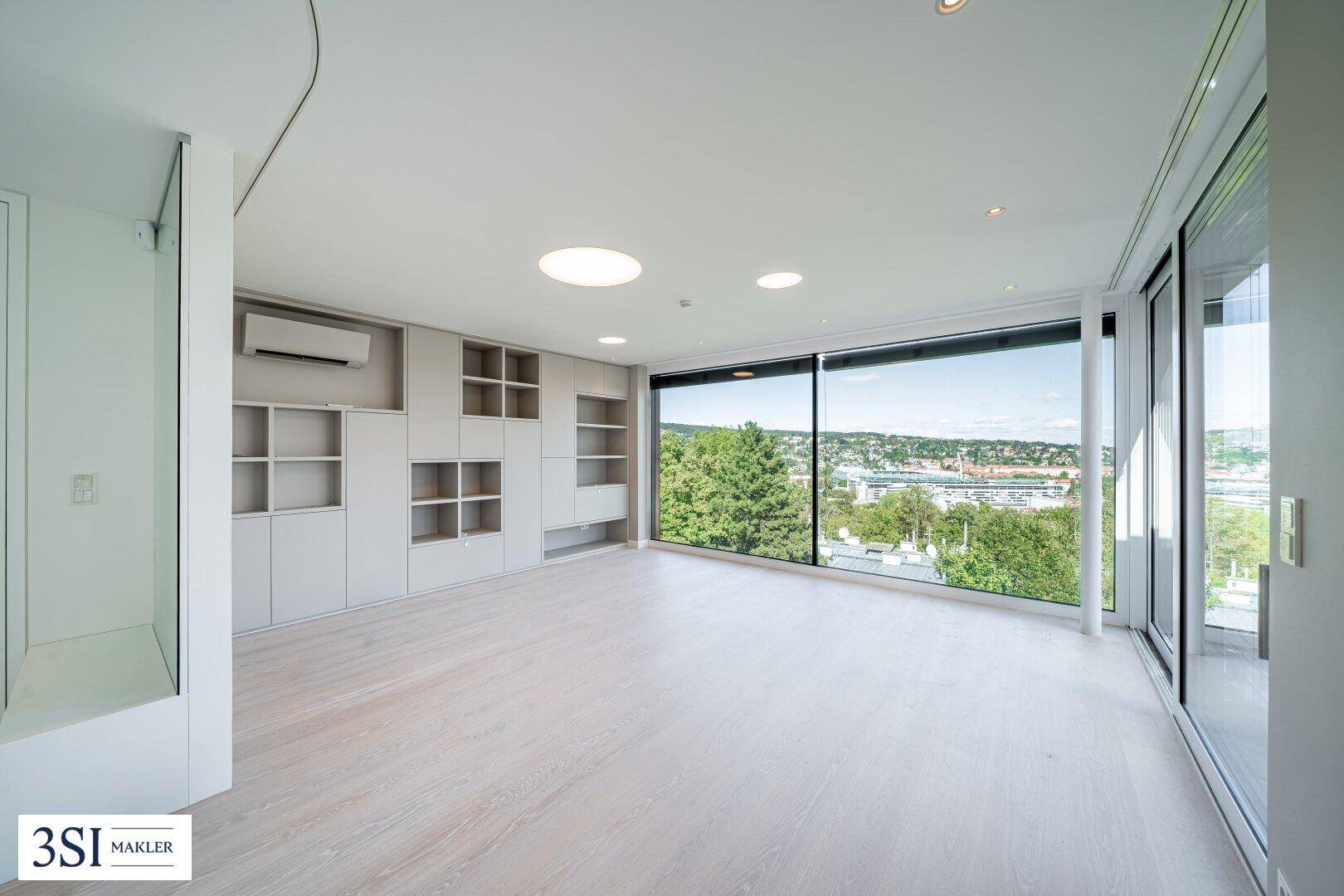 Geräumiges Wohnzimmer mit integrierten Regalen, Klimaanlage und weitem Ausblick über die Stadt.