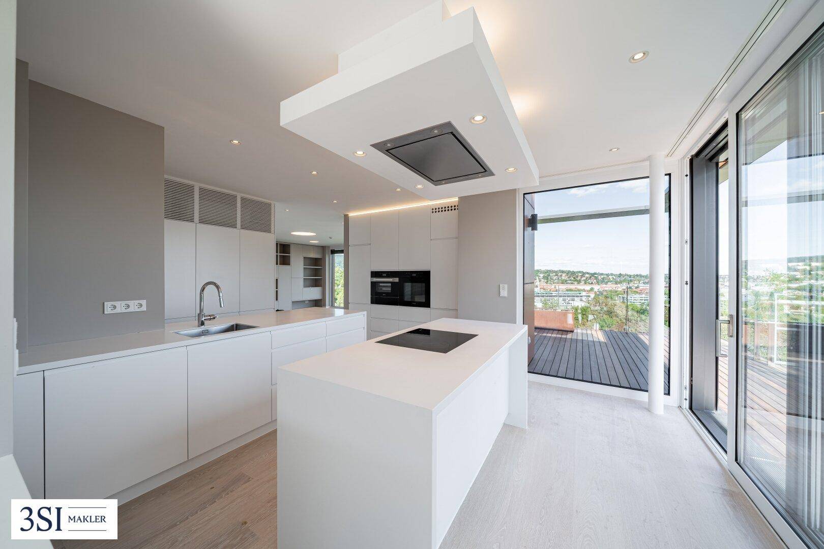 Moderne, offene Küche mit Kochinsel, integrierten Geräten und Zugang zur sonnigen Terrasse.