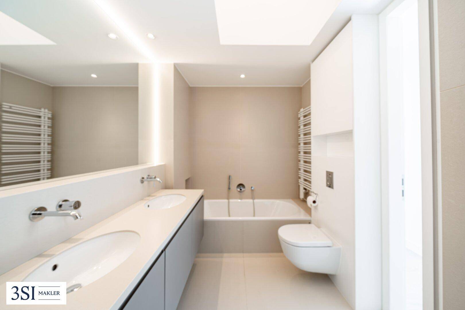 Stilvolles Badezimmer mit Doppelwaschbecken, Badewanne und wandhängendem WC.