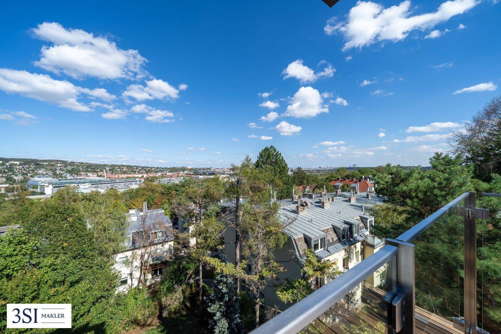Weitläufiger Ausblick vom Balkon über die Stadt und grüne Hügel unter blauem Himmel.