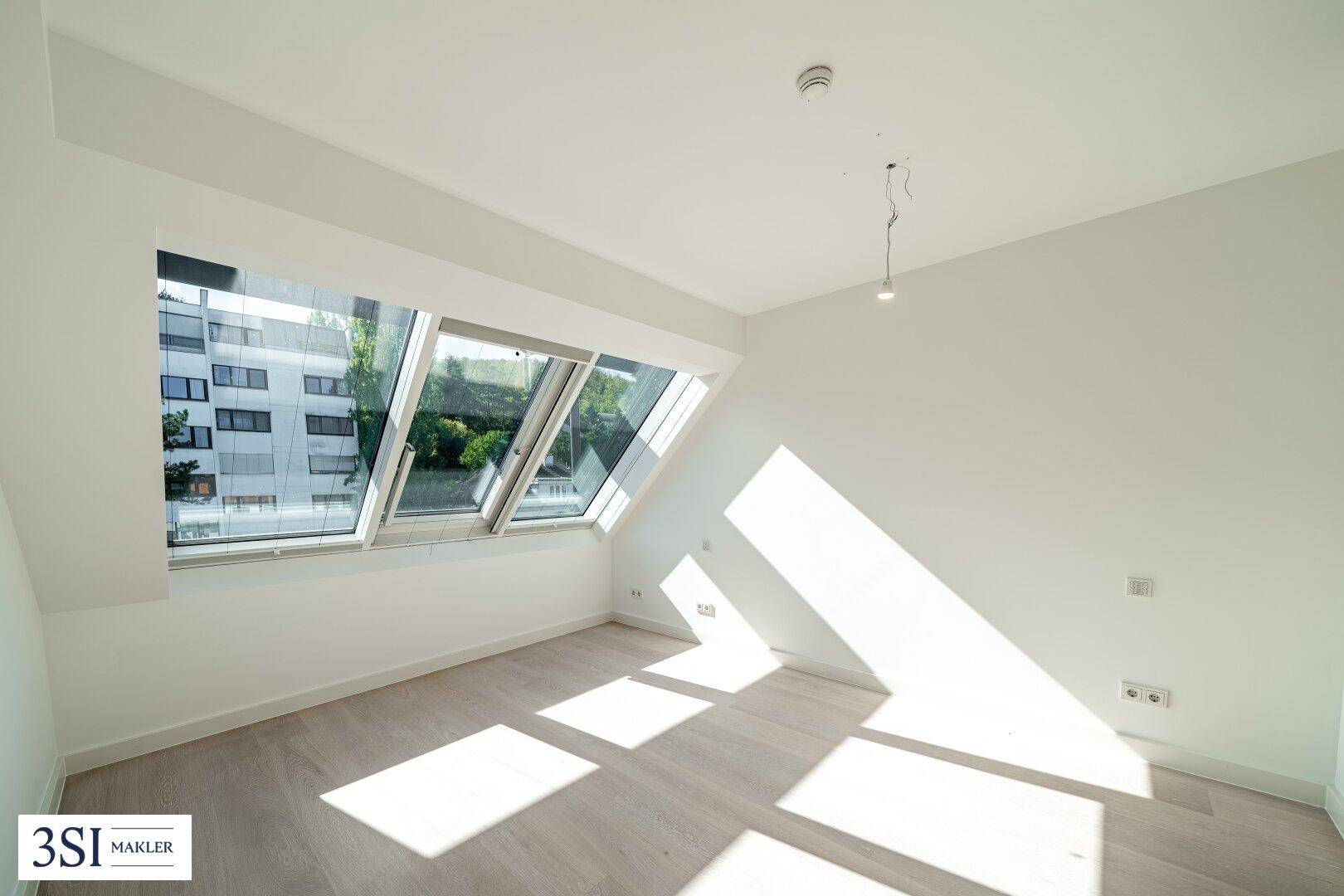 Dachzimmer mit schrägen Wänden und großen Dachfenstern für viel Tageslicht.