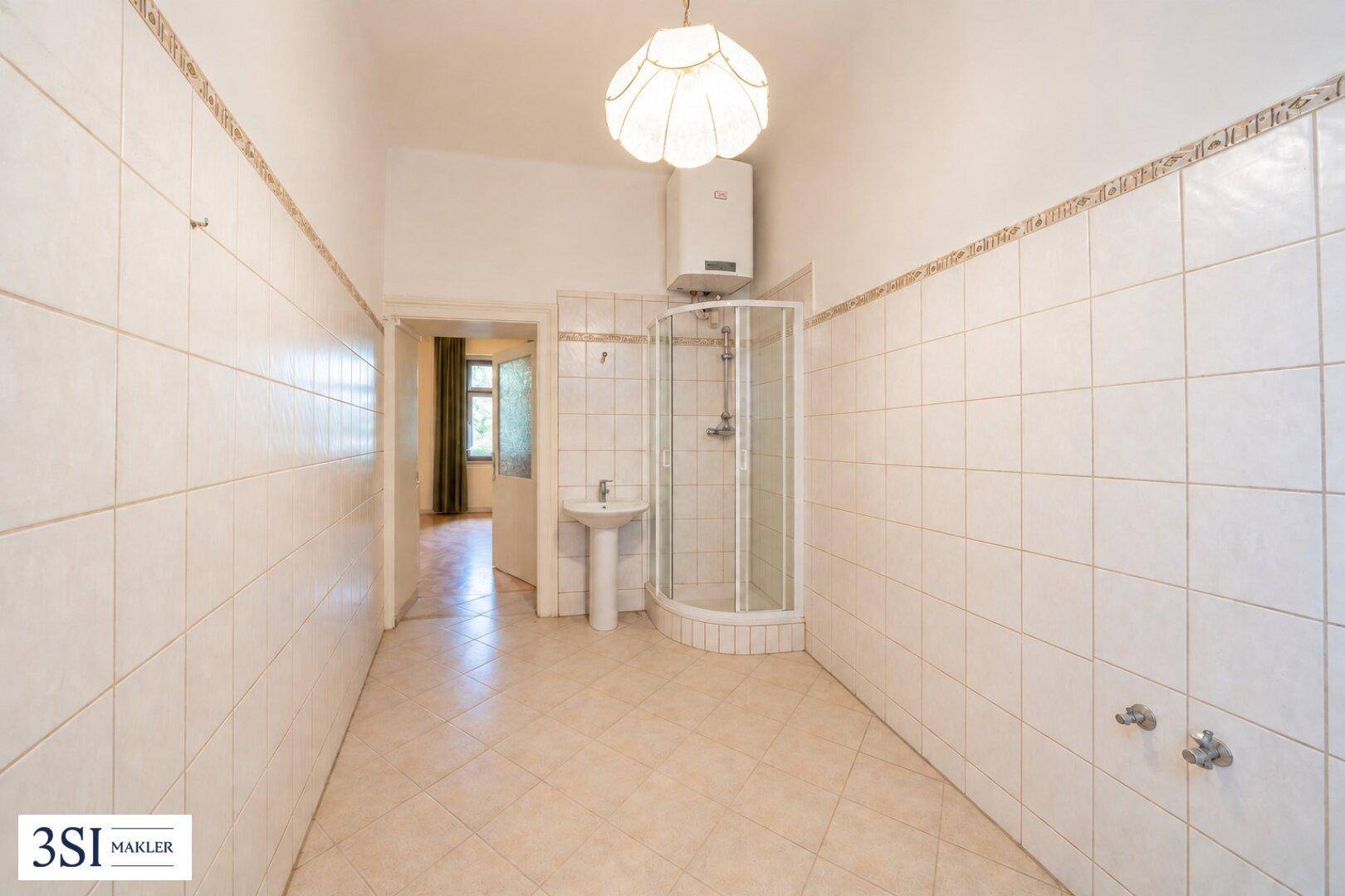 Einfaches Badezimmer mit Duschkabine, Waschbecken und Boiler, vollständig gefliest.