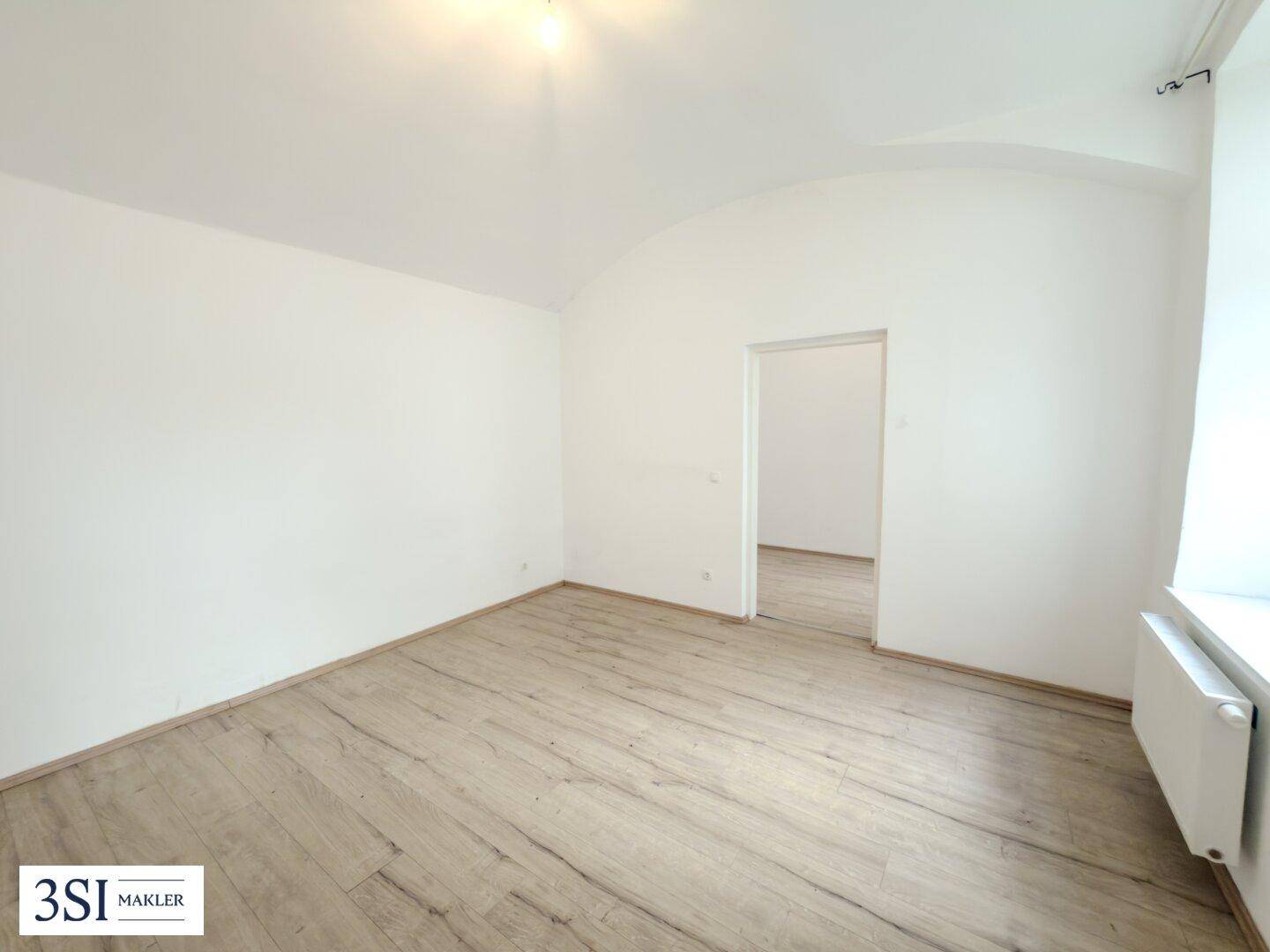 Geräumiges, helles Zimmer mit Laminatboden und weiß gestrichenen Wänden, bereit zur individuellen Gestaltung.