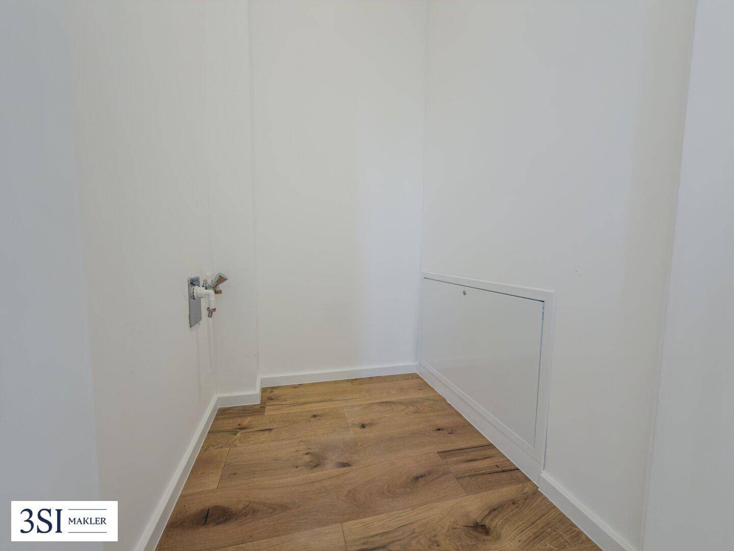 Praktischer Hauswirtschaftsraum mit Holzboden und Anschlüssen für Waschmaschine oder Trockner.