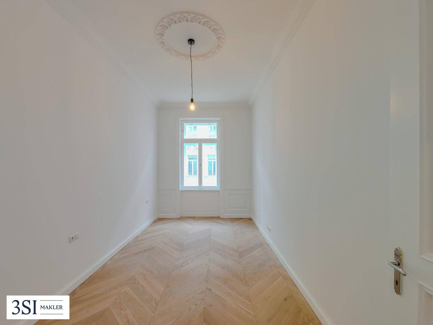 Helles Schlafzimmer mit Fischgrätparkett, Stuckdecke und einem großen Fenster, frisch renoviert.