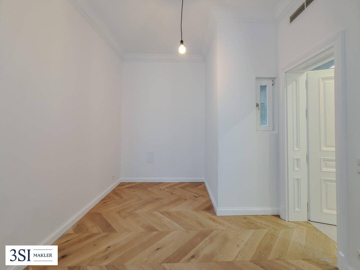 Kleineres Zimmer mit Fischgrätparkett und einem Fenster, ideal als Gäste- oder Kinderzimmer nutzbar.
