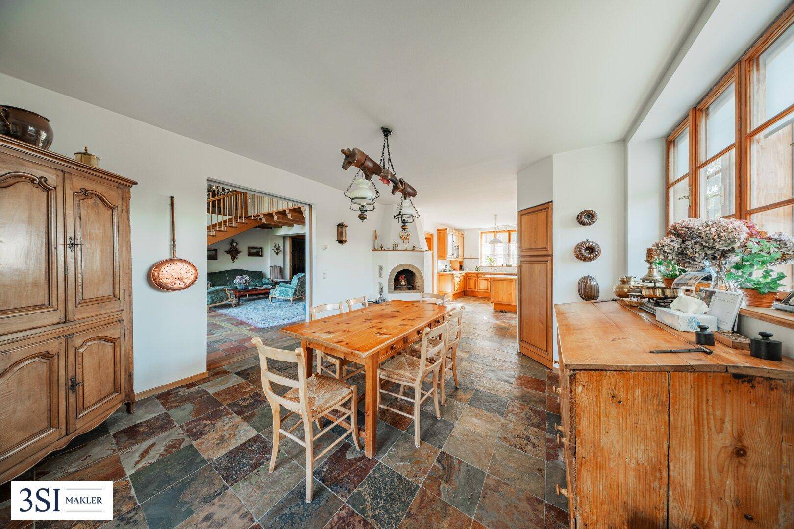 Rustikaler Essbereich mit Holztisch, Schieferboden und Blick in die angrenzende traditionelle Küche.