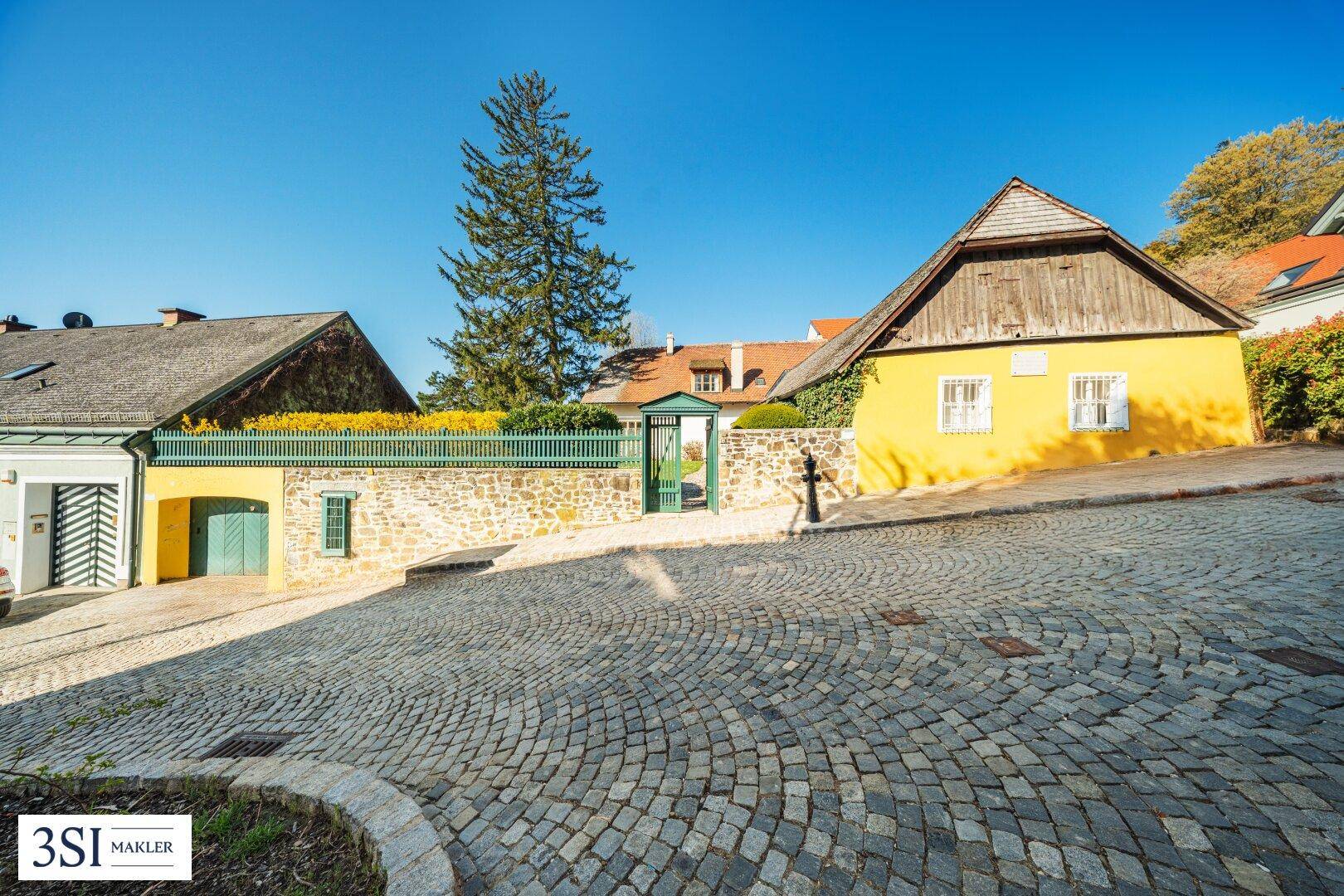 Historisches Anwesen mit Kopfsteinpflaster und traditioneller Architektur in sonniger Lage.
