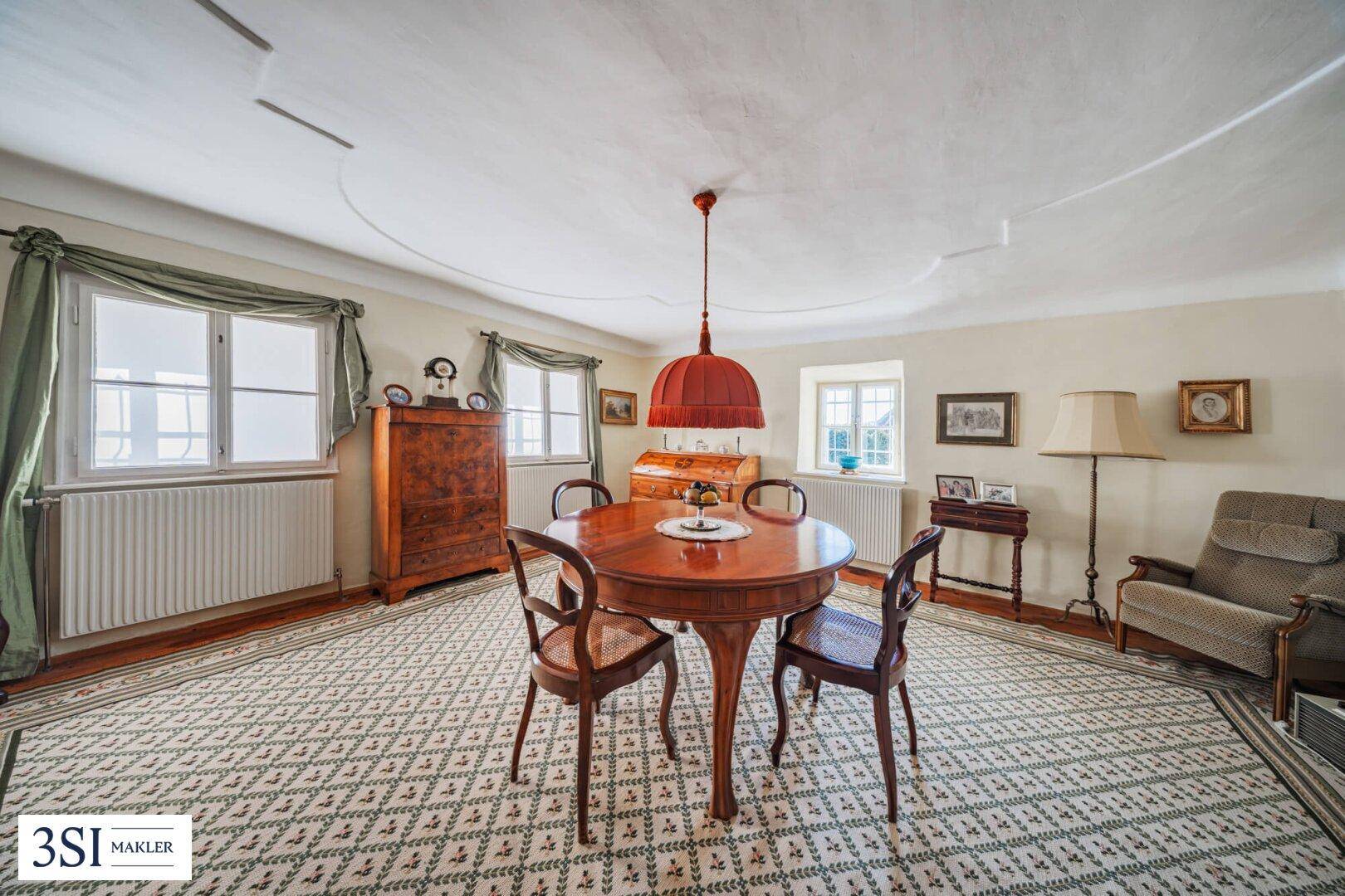 Elegantes Wohnzimmer mit Holzboden, runden Fenstern und klassischer Einrichtung.
