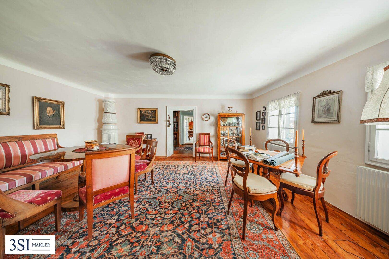Klassischer Essbereich mit Holzboden, elegantem Teppich und traditionellem Kachelofen.