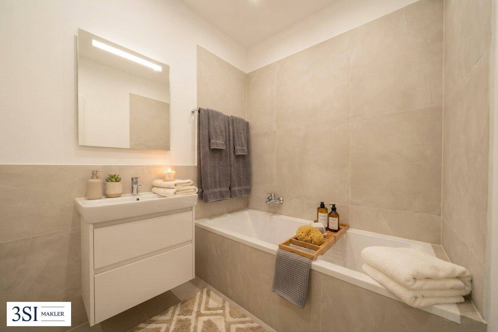 Modernes Badezimmer mit Badewanne, Waschtisch und hellen Fliesen.