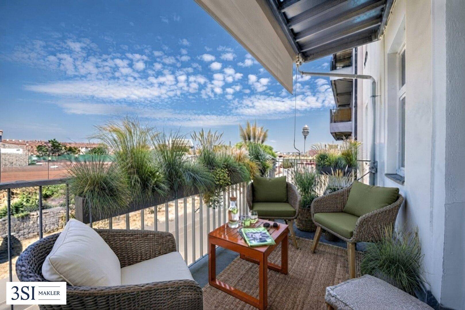 Gemütlicher Balkon mit bequemen Sitzgelegenheiten, vielen Pflanzen und weitem Blick über die Stadt.