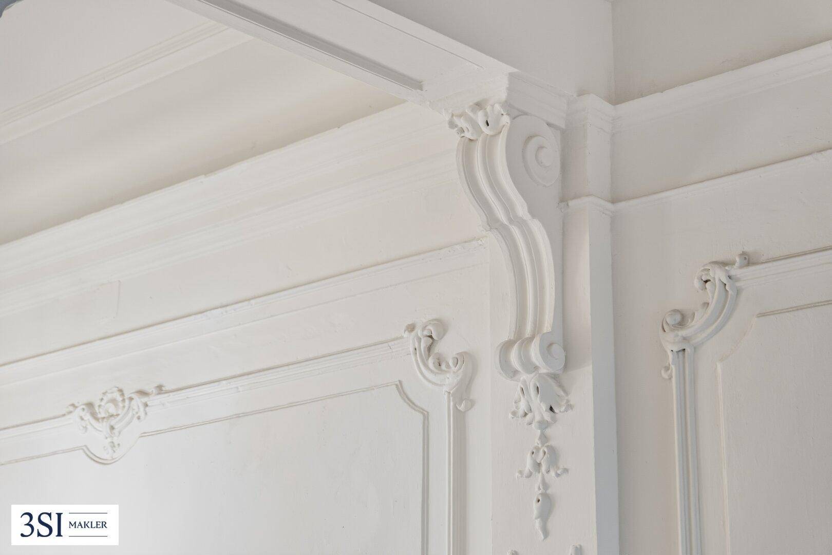 Detailaufnahme von aufwendigen Stuckverzierungen an Wand und Decke in Weiß.