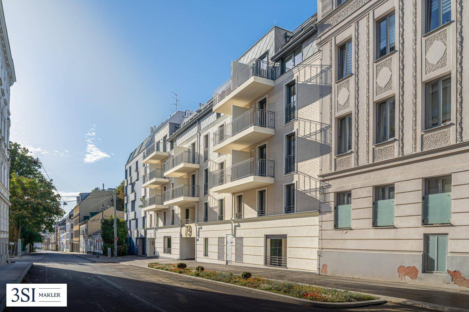 Ansicht des modernen Wohngebäudes von der Straße mit angrenzenden Altbauten und Balkonen.