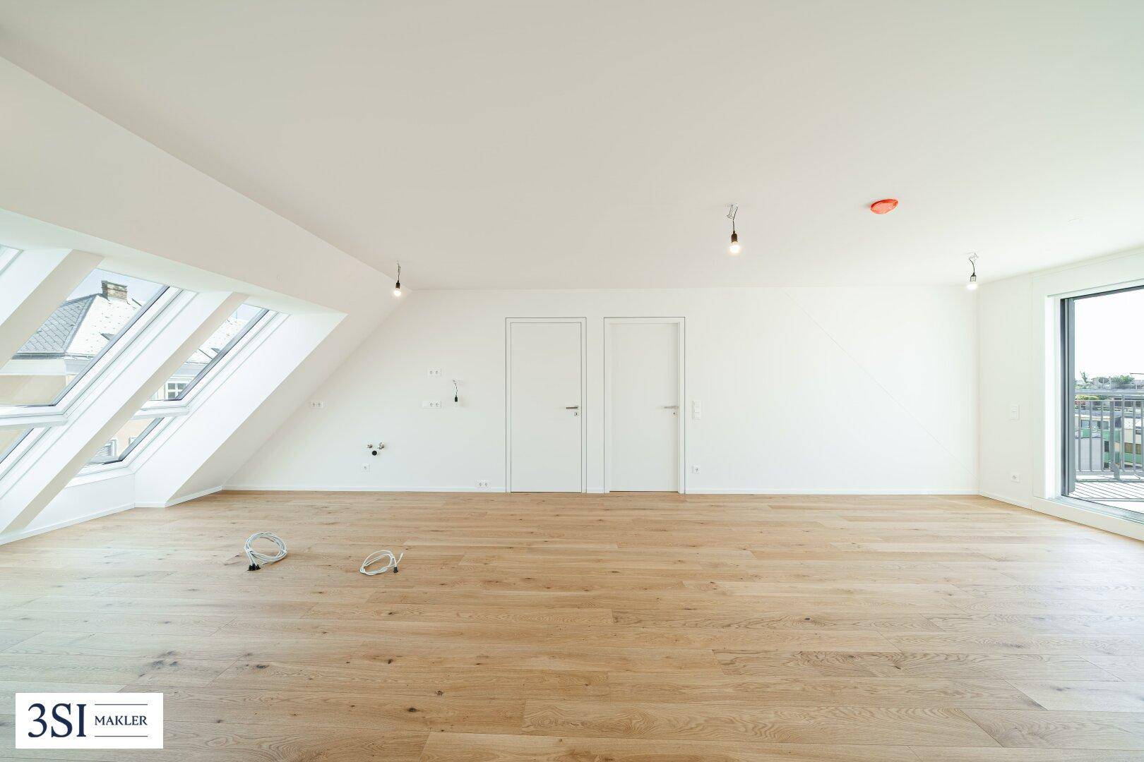 Geräumiger Dachgeschossraum mit Holzboden und großen Dachfenstern, ideal für Wohnzwecke.