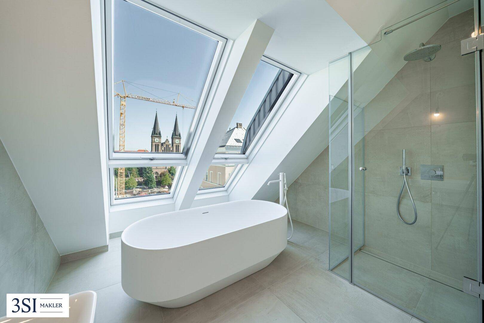 Luxuriöses Dachgeschossbad mit freistehender Badewanne, begehbarer Dusche und Stadtblick.