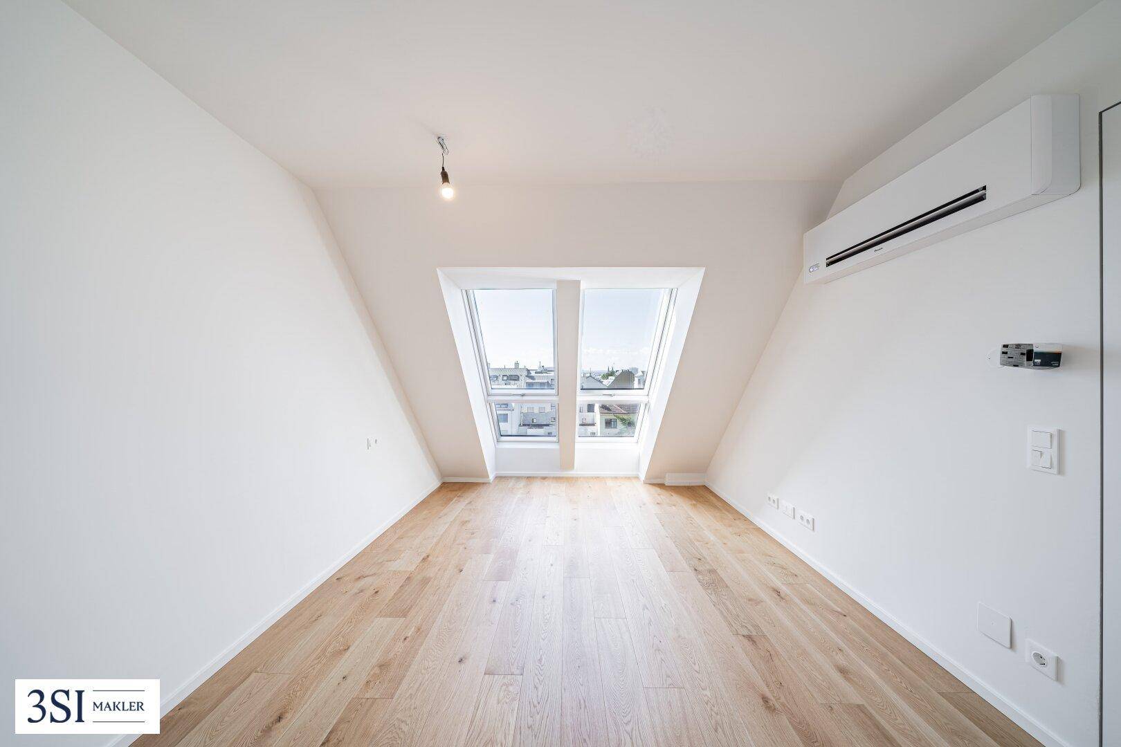 Helles Schlafzimmer im Dachgeschoss mit Holzboden, Klimaanlage und Dachfenstern für viel Licht.