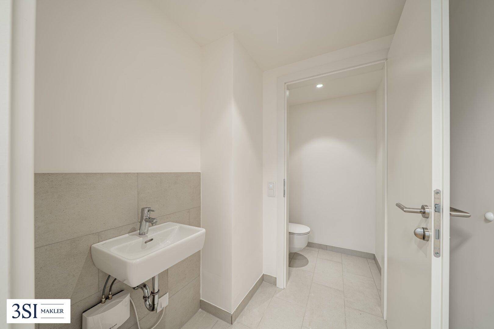 Modernes Gäste-WC mit weißem Waschbecken und hellen Fliesen, funktional und sauber.
