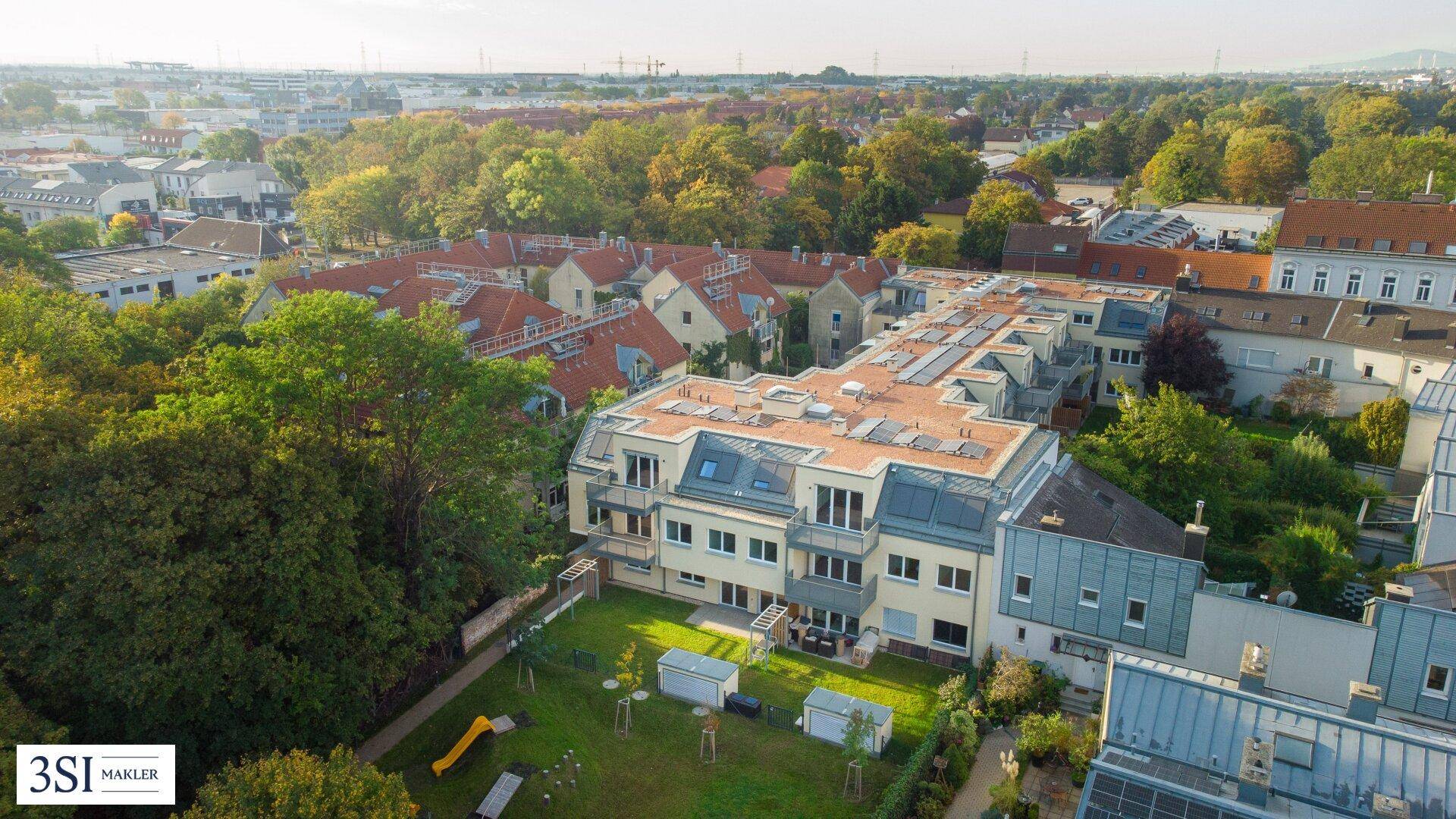 Luftaufnahme eines modernen Wohnkomplexes mit großem Gemeinschaftsgarten und Spielplatz.