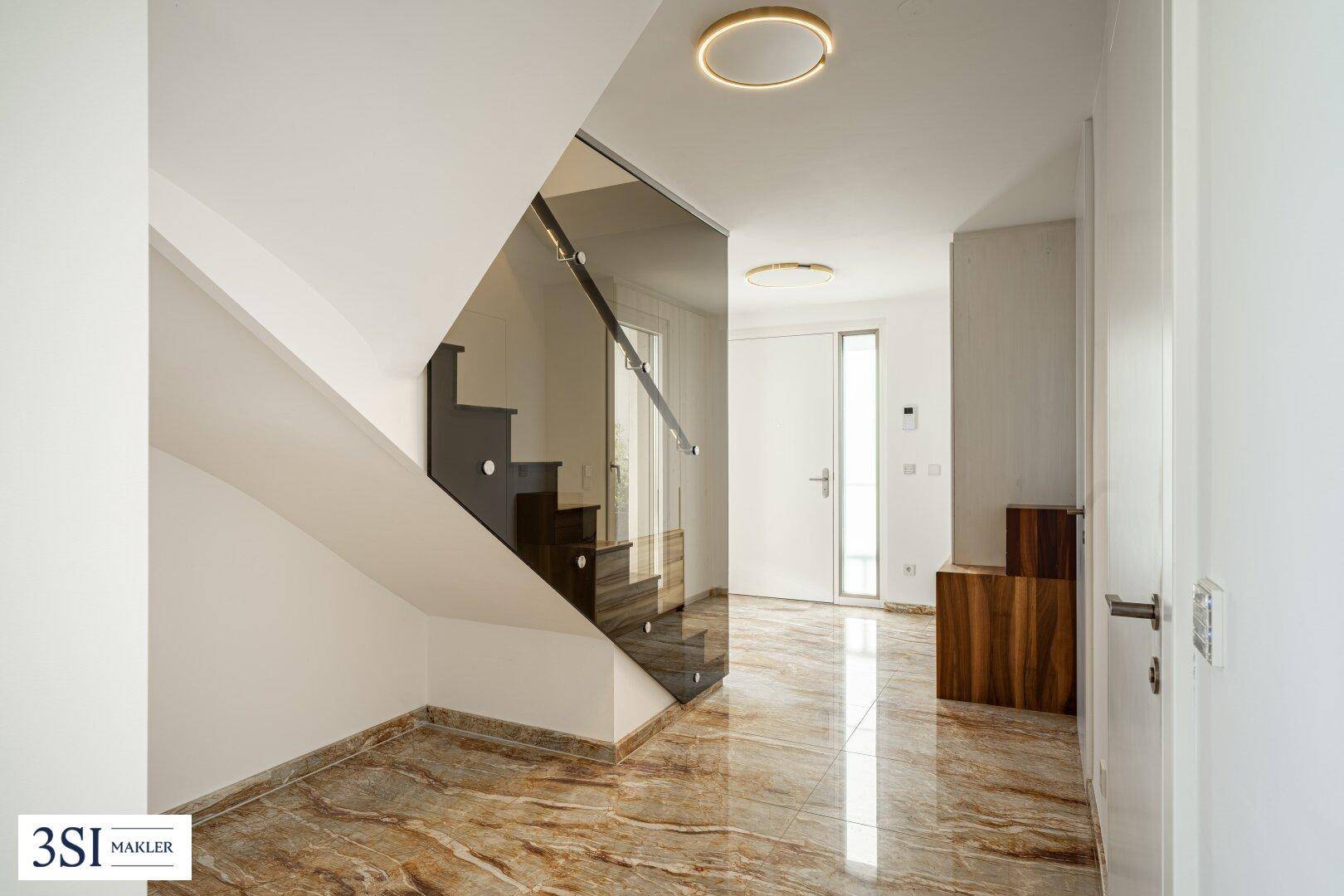 Heller Flur mit moderner Treppe aus Holz und Glas, die zu den oberen Etagen führt.