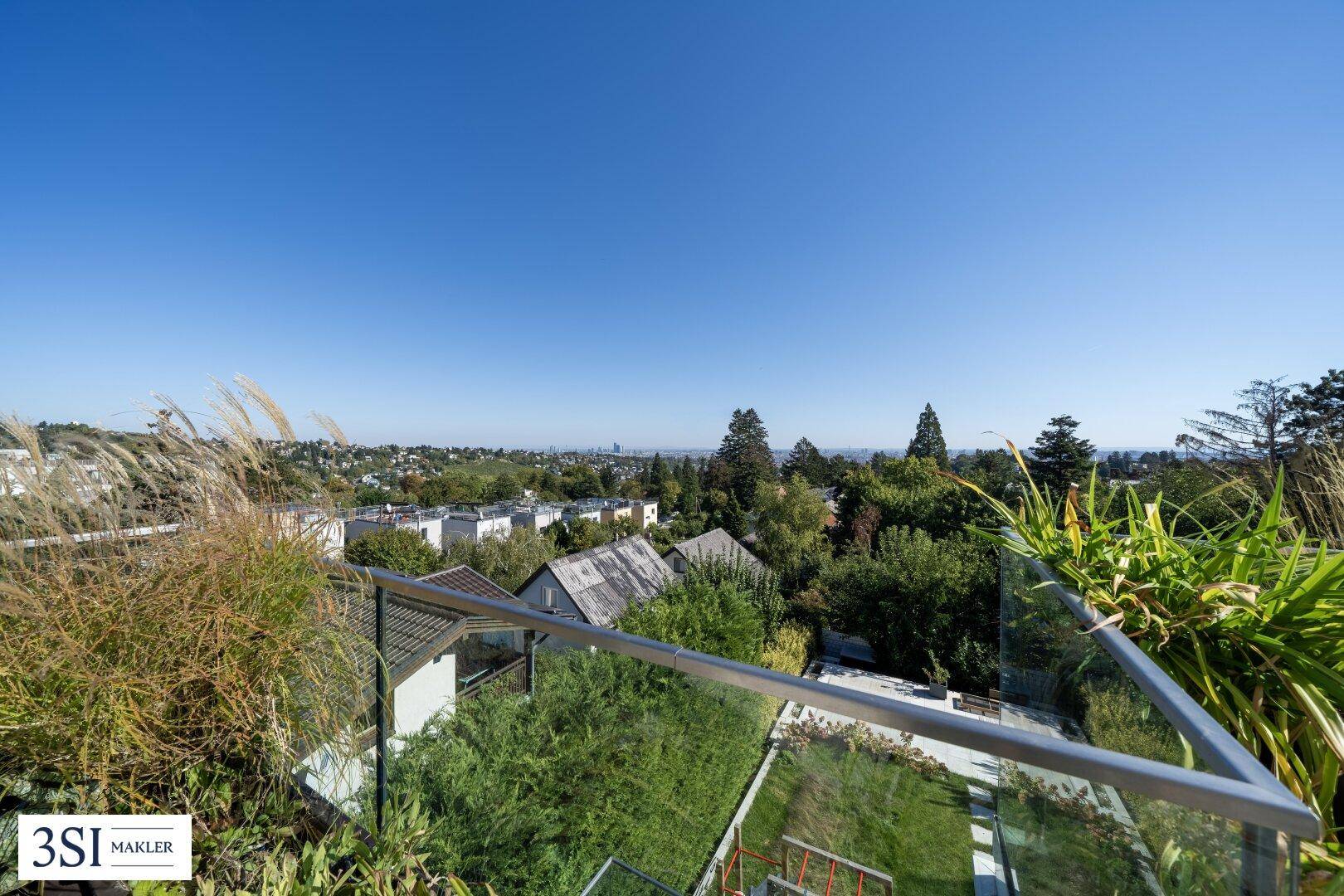 Weitläufiger Blick über die Dächer der Stadt und die grüne Umgebung von einer erhöhten Position.