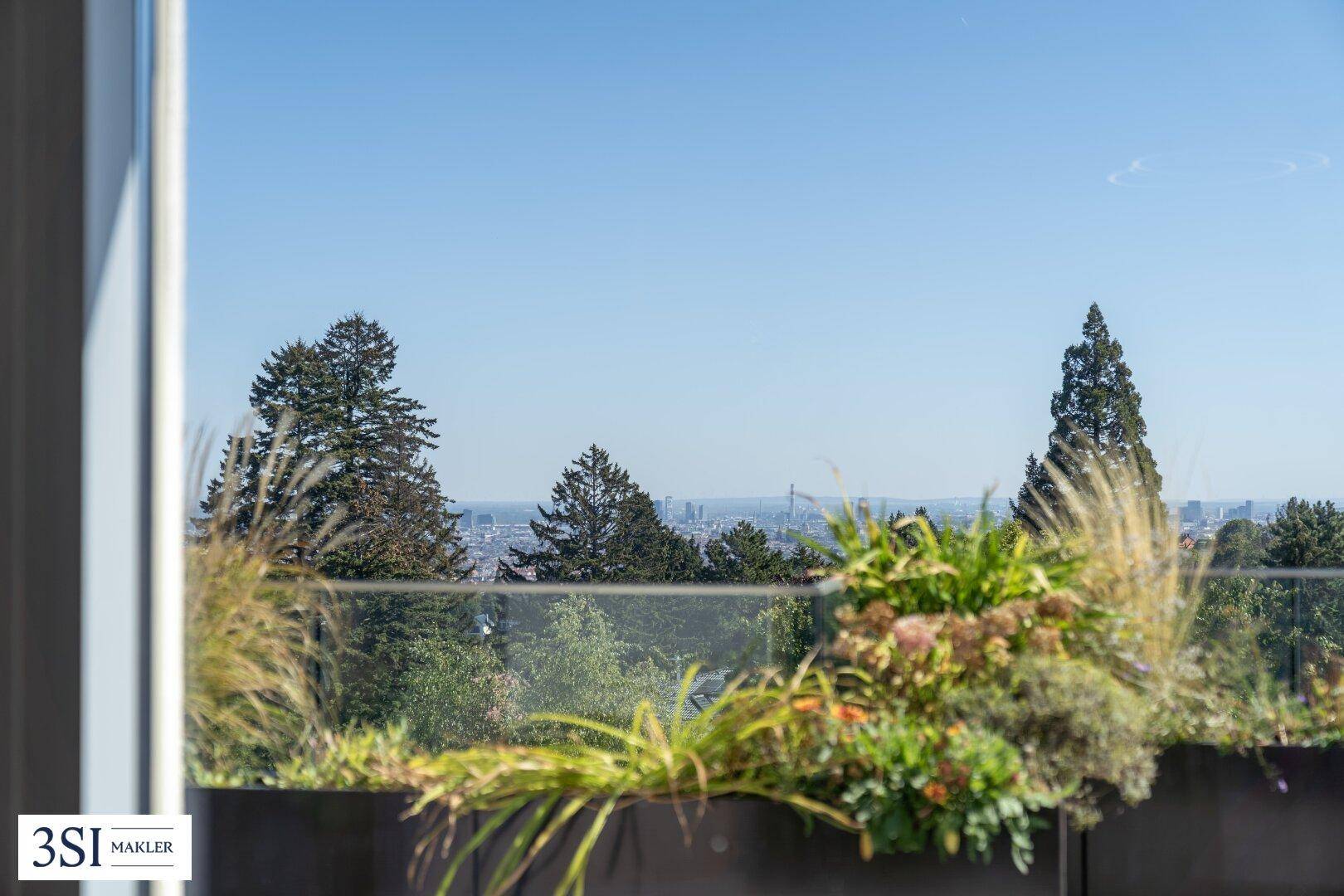 Blick durch ein Fenster auf die grüne Umgebung und die Skyline der Stadt in der Ferne.