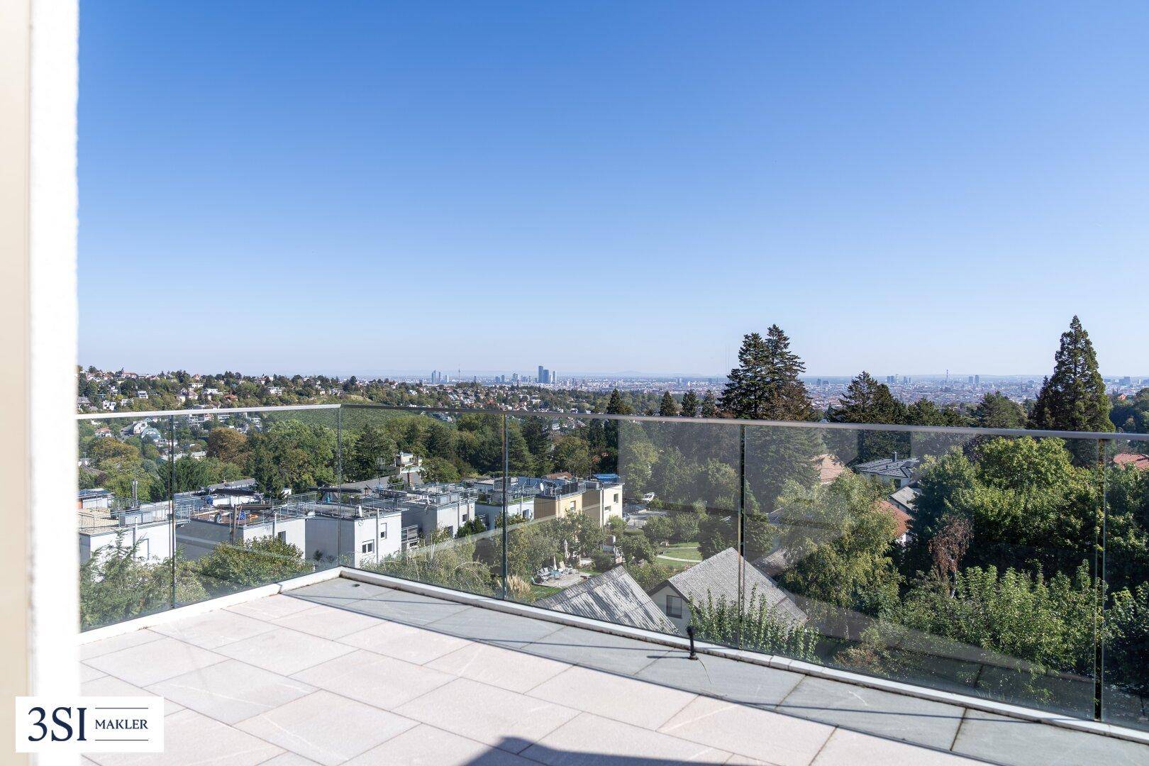 Große Dachterrasse mit Glasgeländer und weitem Blick über die Stadt und die grüne Umgebung.