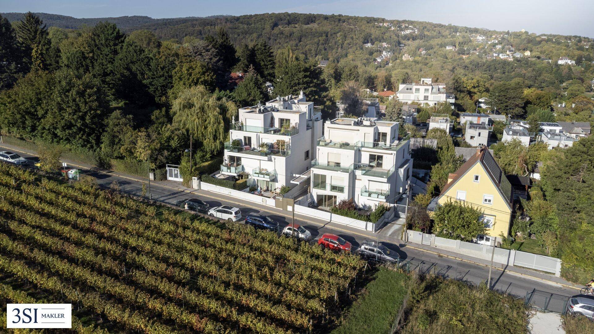 Moderne Wohnanlage mit mehreren Einheiten, umgeben von Weinbergen und grüner Landschaft.