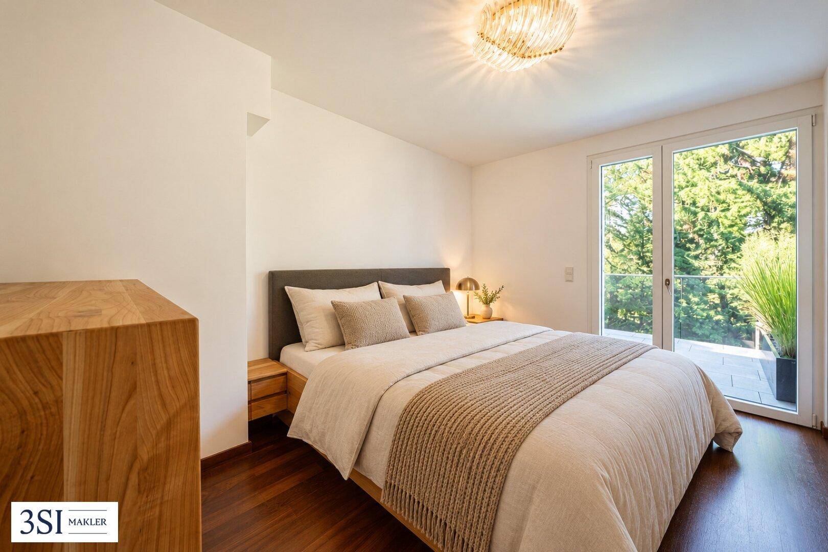Helles Schlafzimmer mit großem Doppelbett, Holzboden und Zugang zu einem französischen Balkon.