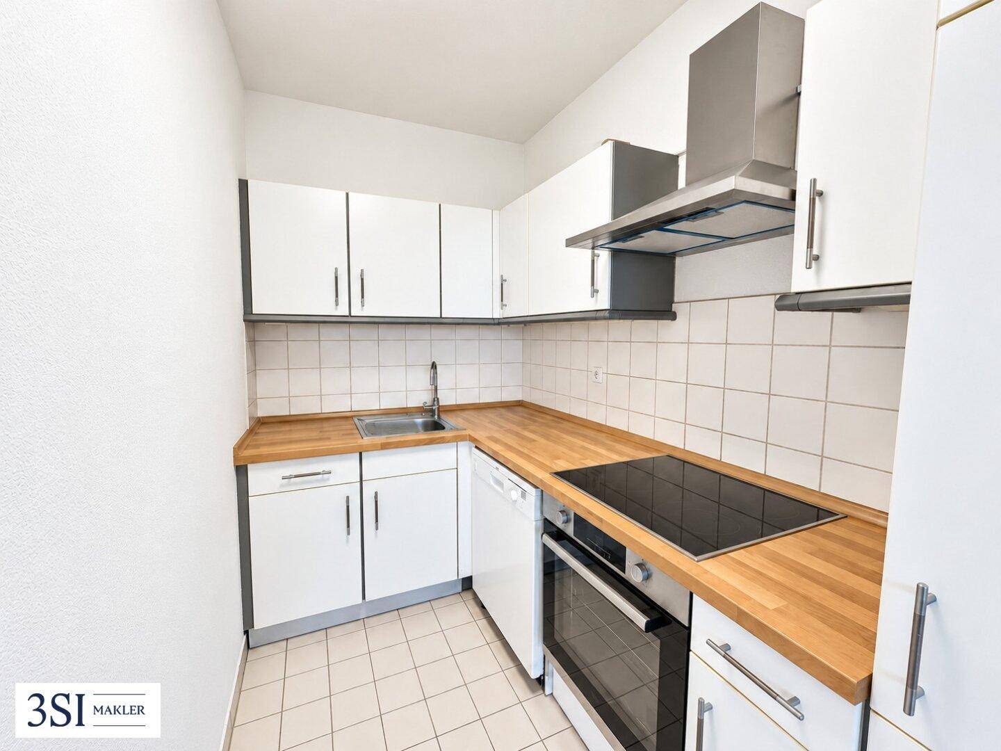 Funktionale Küche mit weißen Schränken, Holz-Arbeitsplatten und integrierten modernen Geräten.