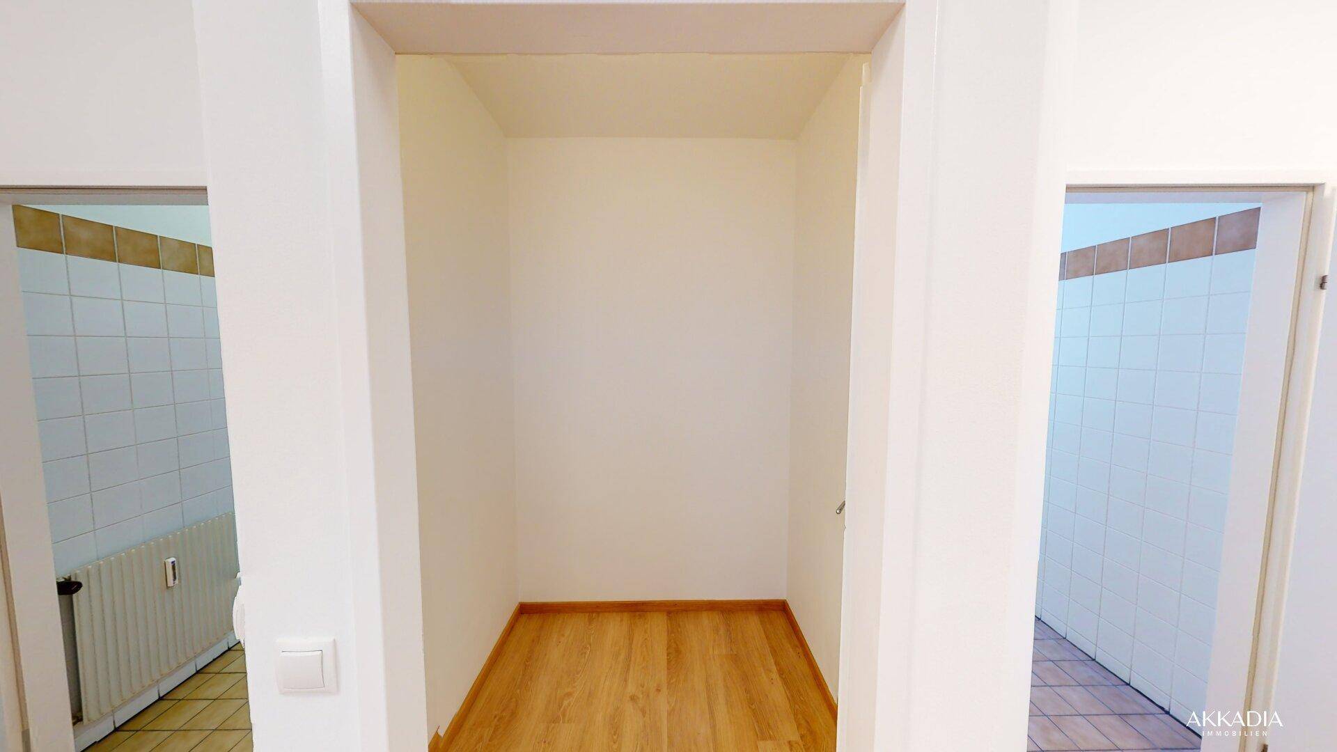 Kleiner Abstellraum mit hellem Holzboden, umgeben von gefliesten Bereichen.