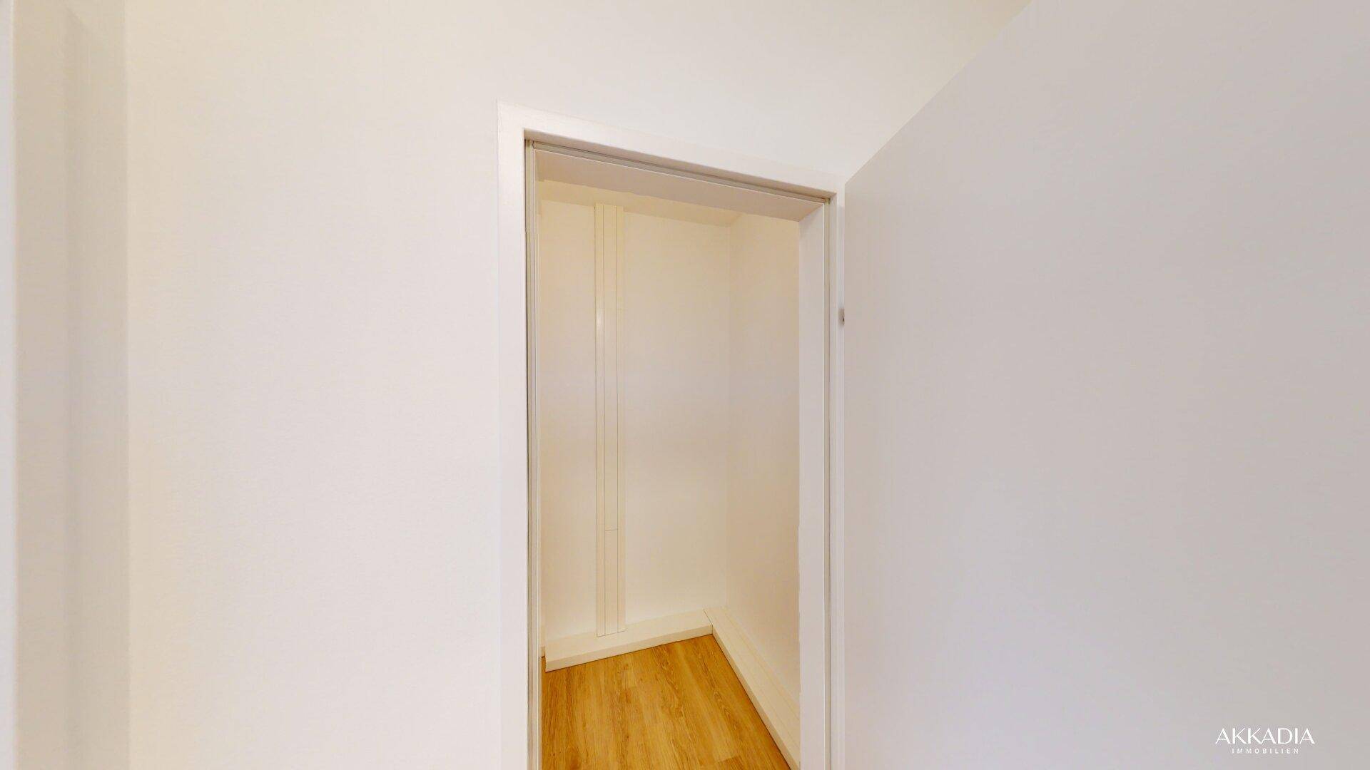 Kleiner, leerer Wandschrank oder Abstellraum mit hellem Holzboden und weißen Wänden.