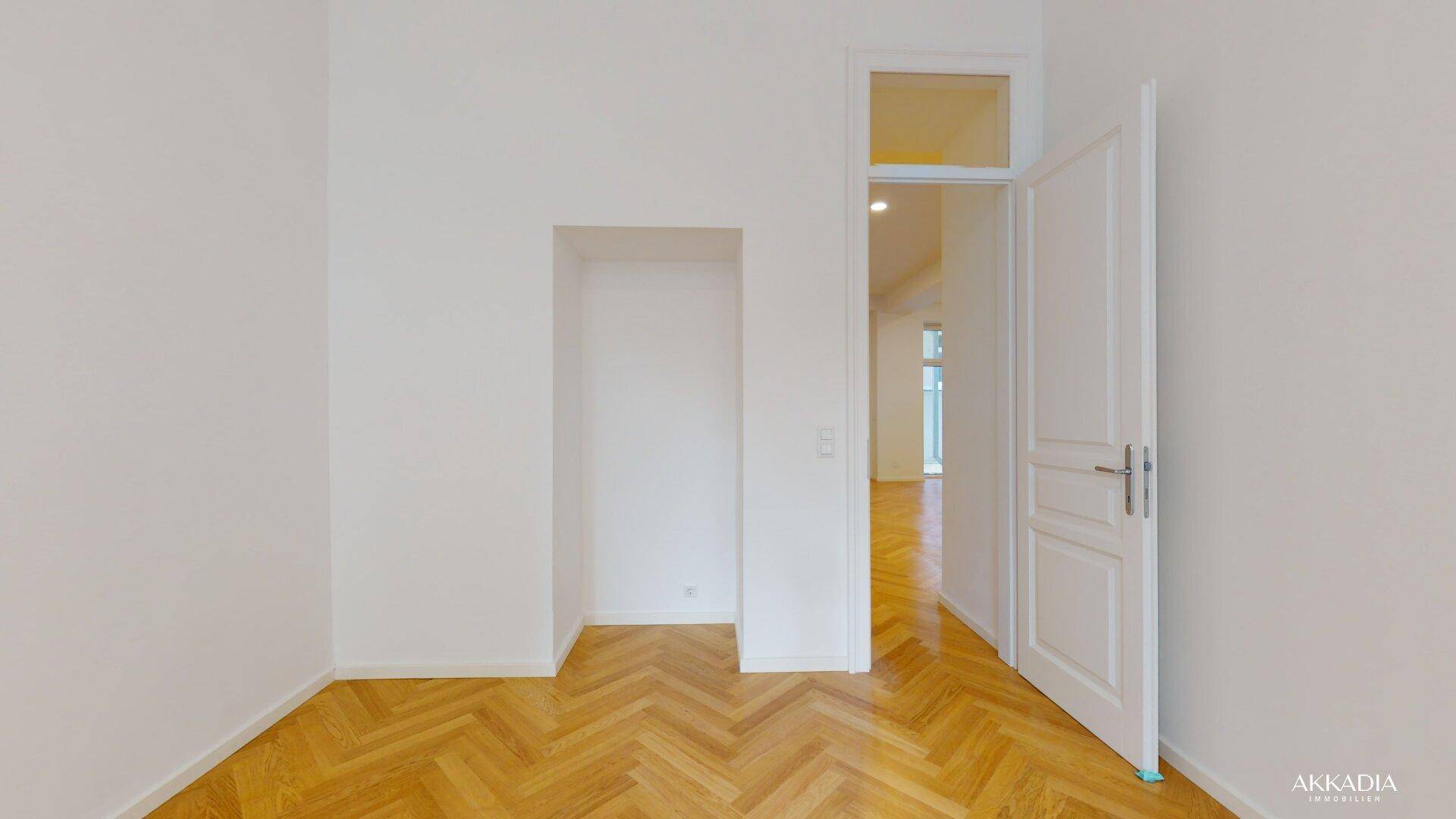 Helles Zimmer mit Fischgrätparkett und einer praktischen Nische für Stauraum oder Dekoration.