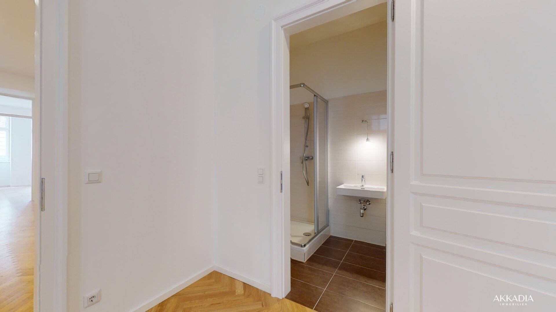 Modernes Badezimmer mit Duschkabine, Waschbecken und hellen Wand- und Bodenfliesen.