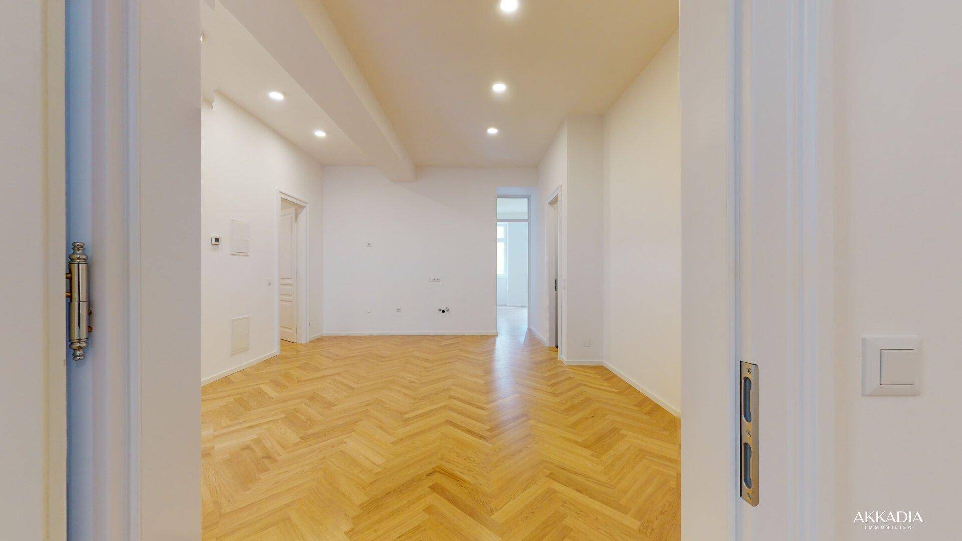 Geräumiges, helles Zimmer mit klassischem Fischgrätparkett und modernen Deckenspots.