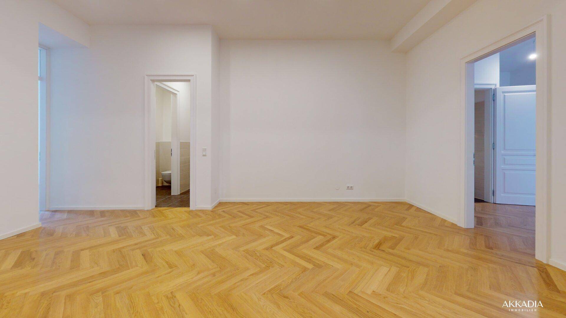 Geräumiges, helles Zimmer mit klassischem Fischgrätparkett und modernen Deckenspots.
