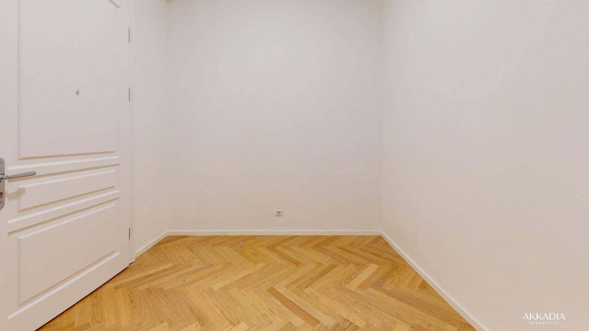 Kleiner, heller Raum mit Fischgrätparkett und weiß gestrichenen Wänden.