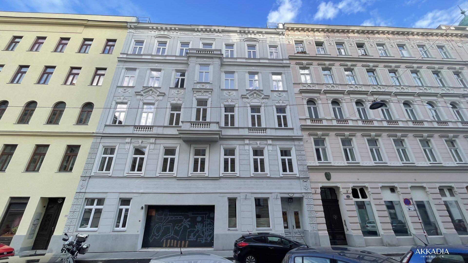 Historische Fassade eines Mehrfamilienhauses mit vielen Fenstern und Balkonen.