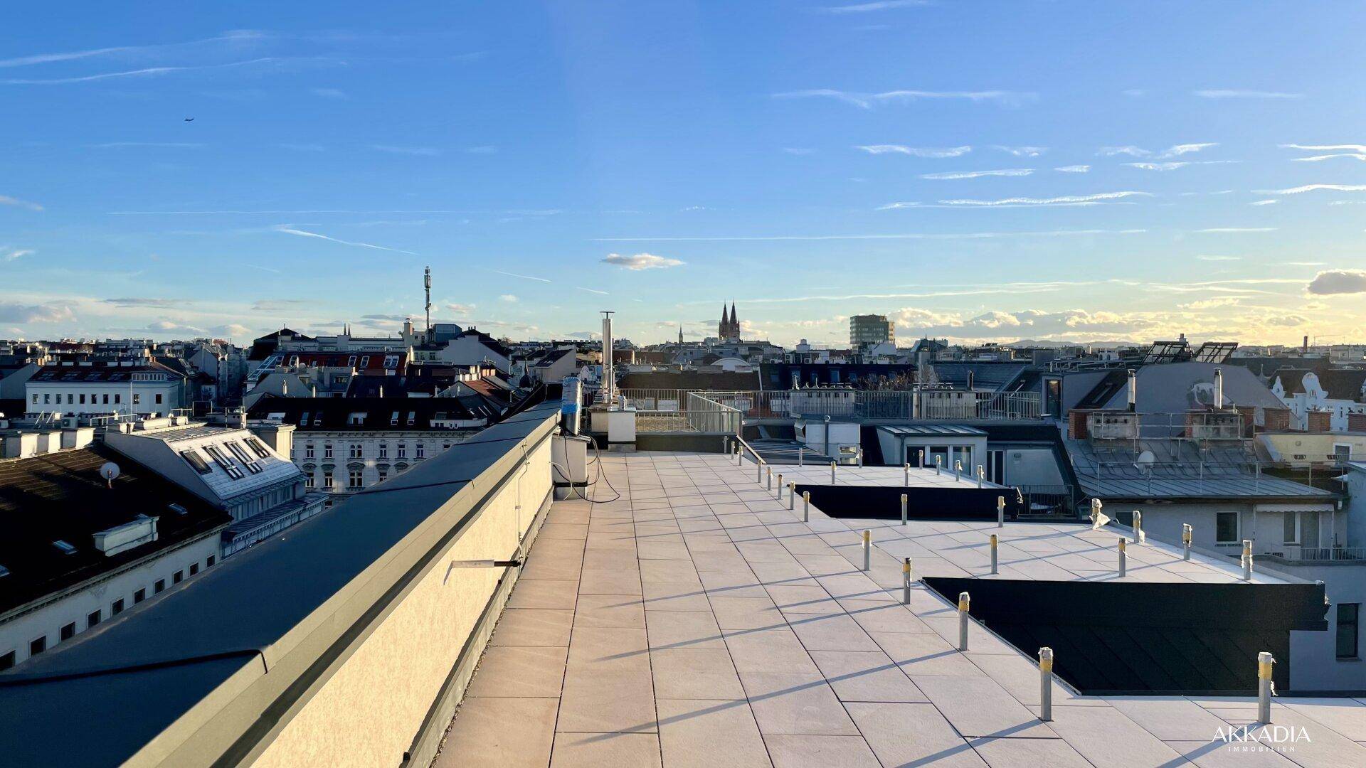 Weitläufige Dachterrasse mit Fliesenboden und Panoramablick über die Stadt.