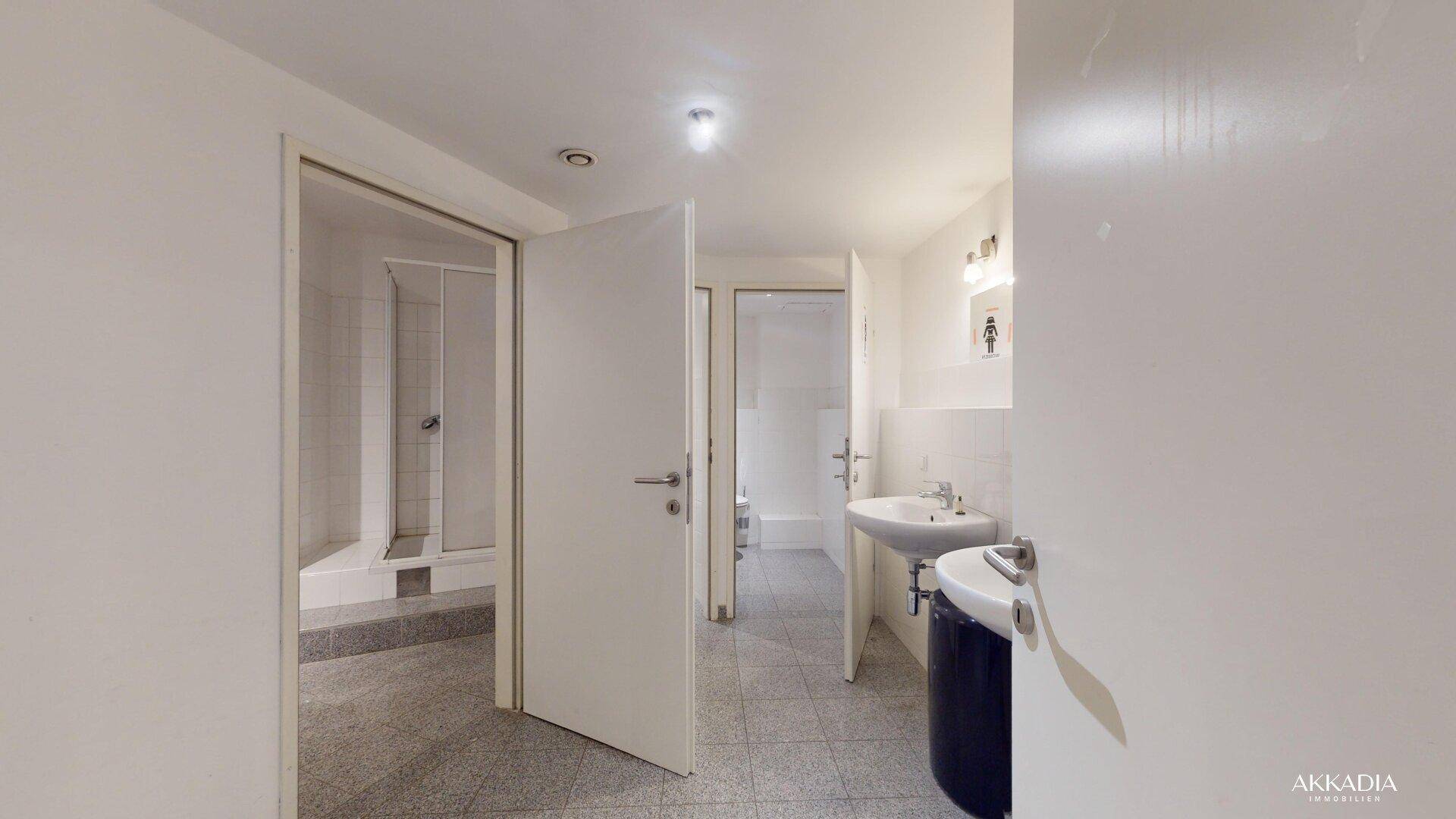 Mehrere Badezimmer mit Duschen und Waschbecken, ideal für gewerbliche oder öffentliche Nutzung.