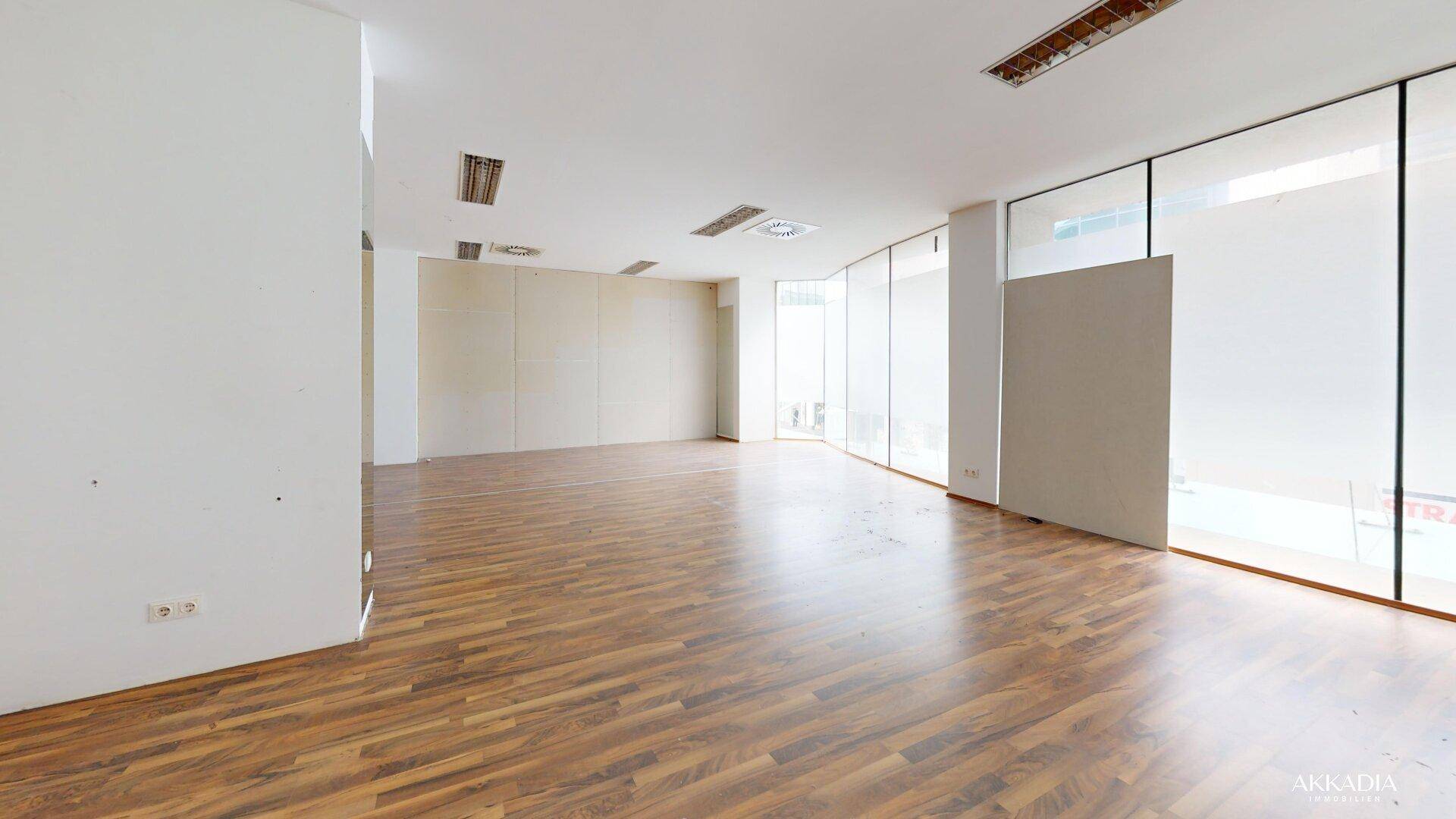 Heller Büroraum mit Laminatboden und großen Fenstern, ideal für eine moderne Arbeitsumgebung.