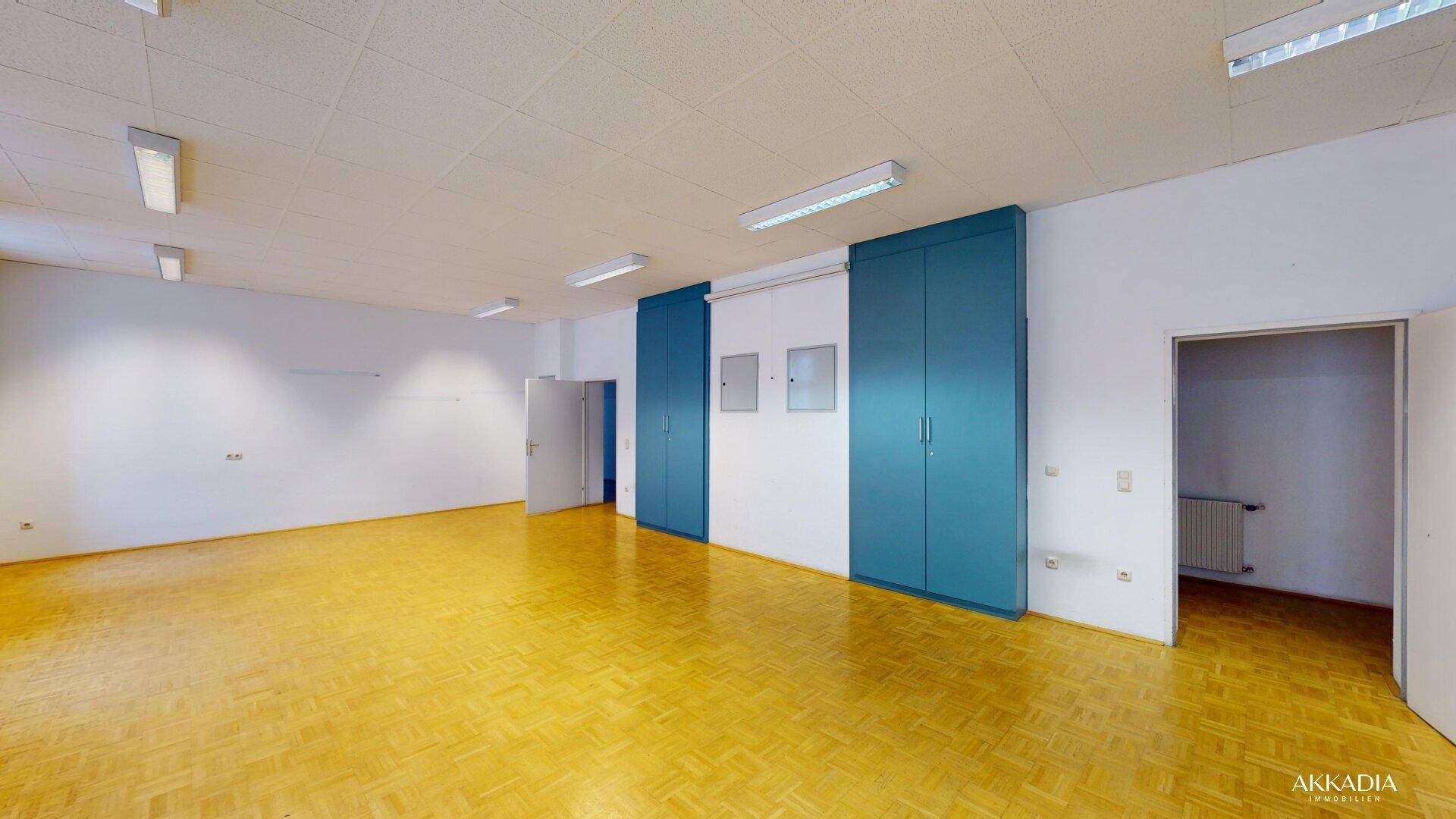 Weitläufiger Raum mit hellen Wänden, Parkettboden und praktischen blauen Einbauschränken, bereit zur Nutzung.