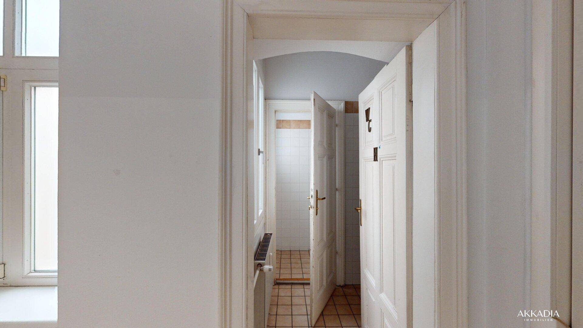 Durchgangsbereich mit Fliesenboden, der zu einem Badezimmer oder Toilettenbereich führt.
