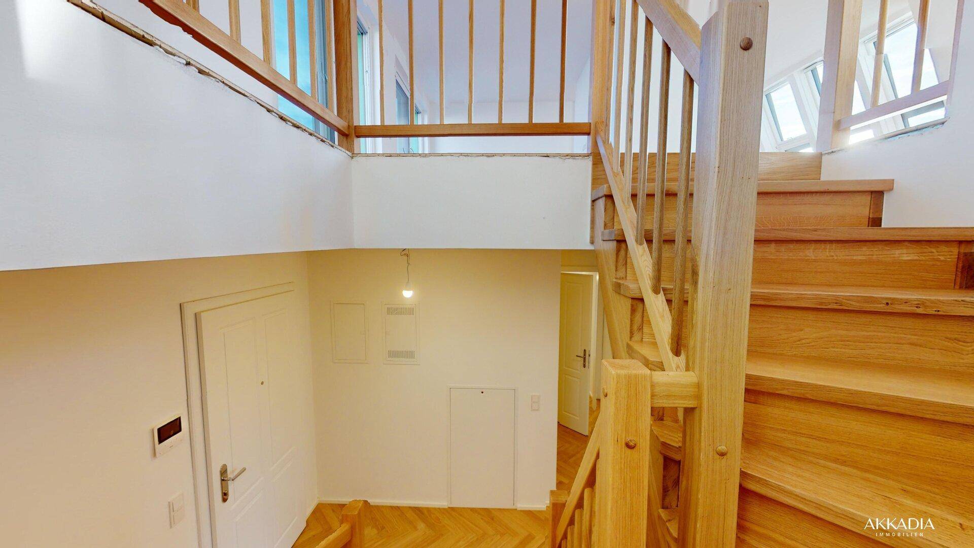 Holztreppe führt zu einem unteren Bereich mit weißen Türen und hellem Ambiente.