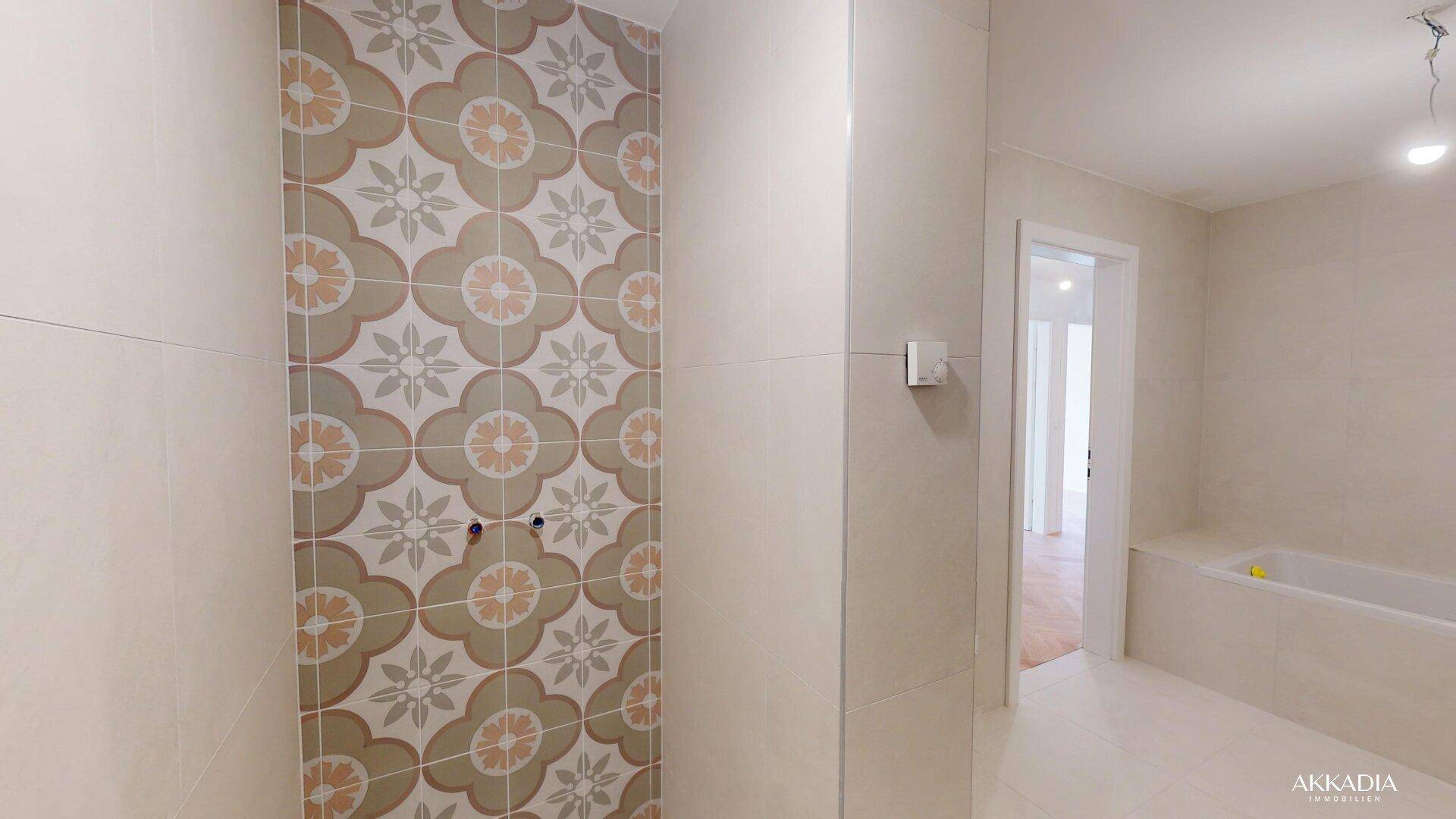 Modernes Badezimmer mit gemusterten Fliesen im Duschbereich und einer Badewanne.
