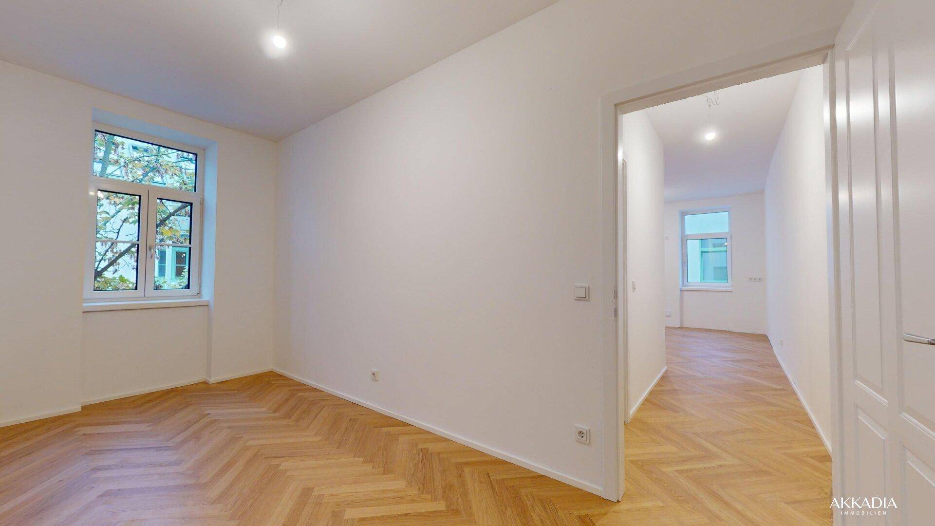 Geräumiges, helles Zimmer mit Fischgrätparkett und weißen Wänden, bereit für die Einrichtung.