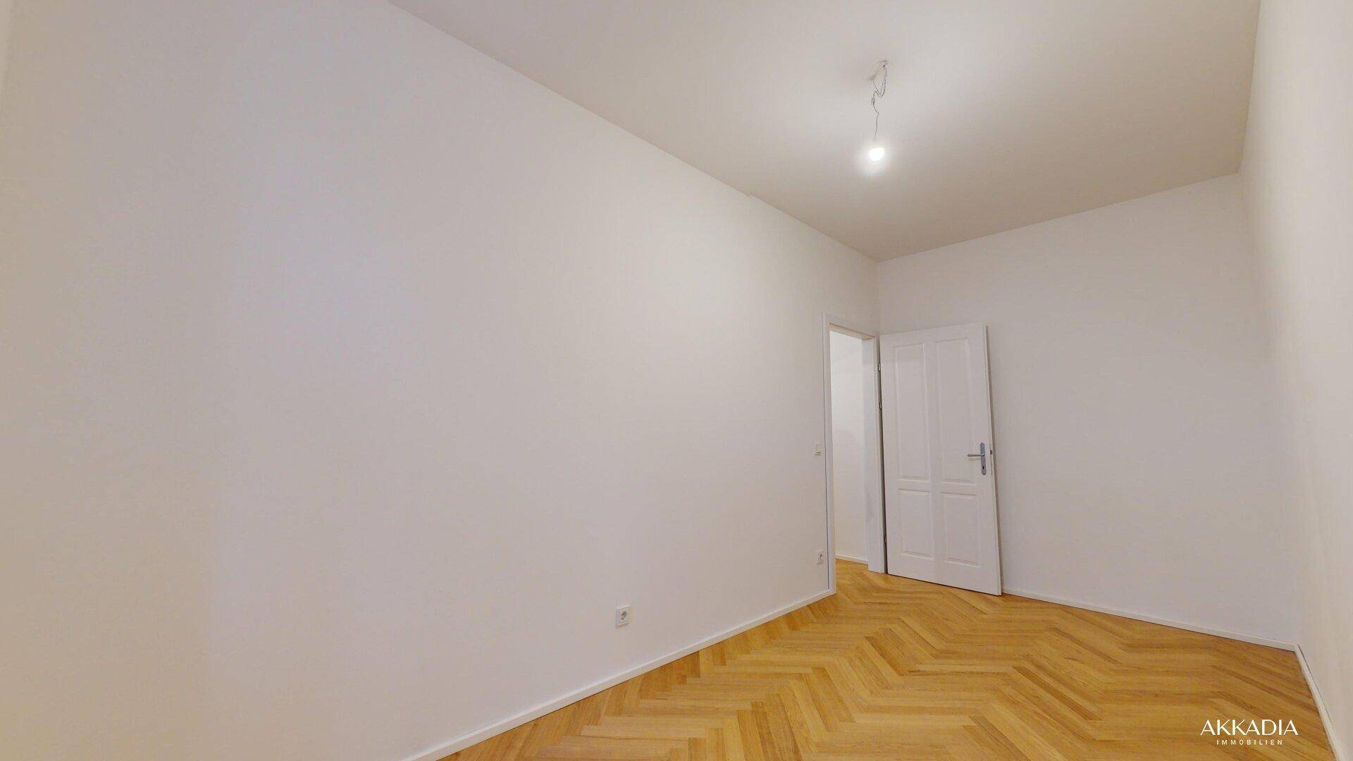 Leeres Zimmer mit Fischgrätparkett und weißen Wänden, ideal als Schlafzimmer oder Arbeitszimmer.