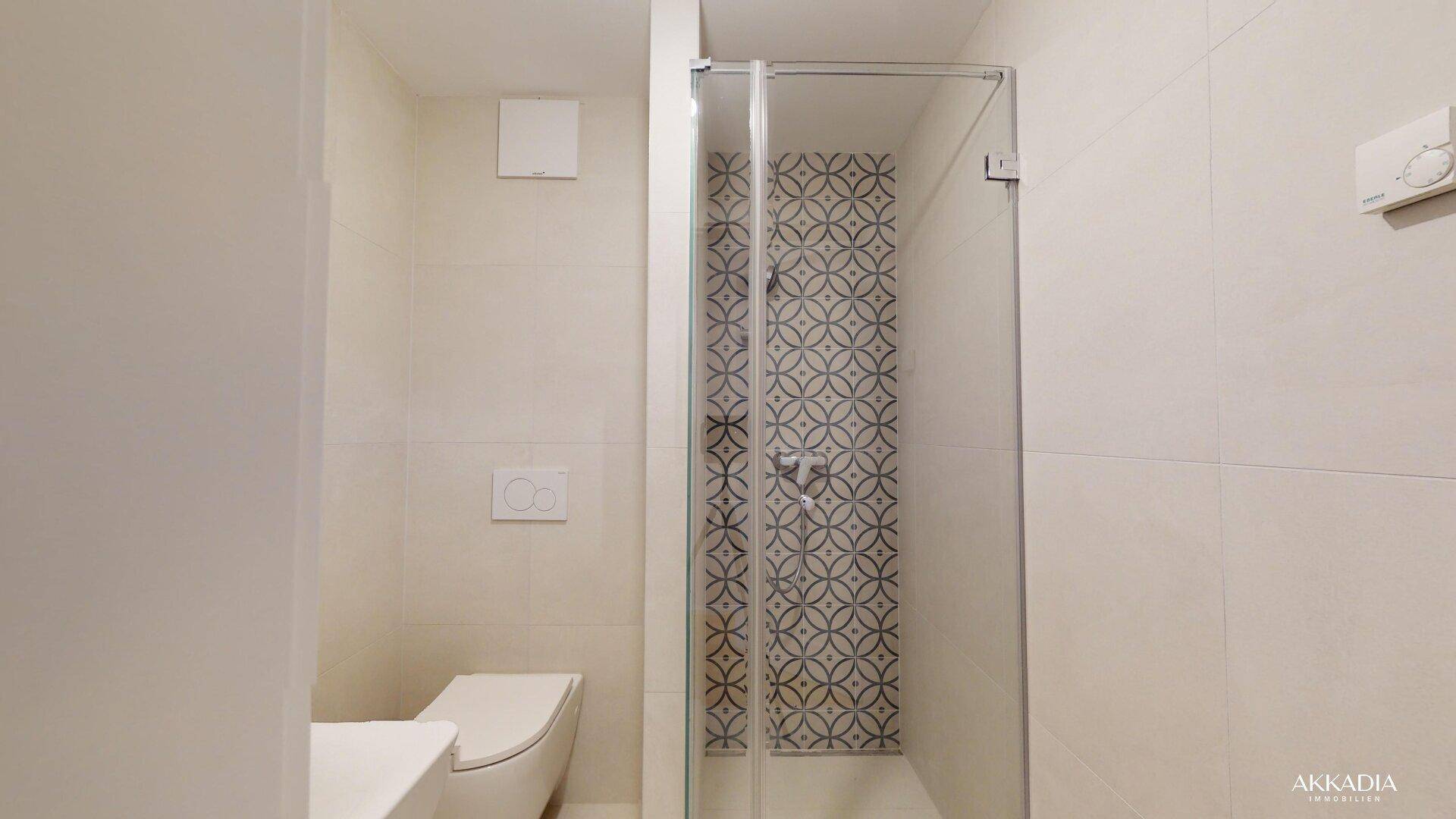 Modernes Badezimmer mit Duschkabine, Wand-WC und dekorativen Fliesen.