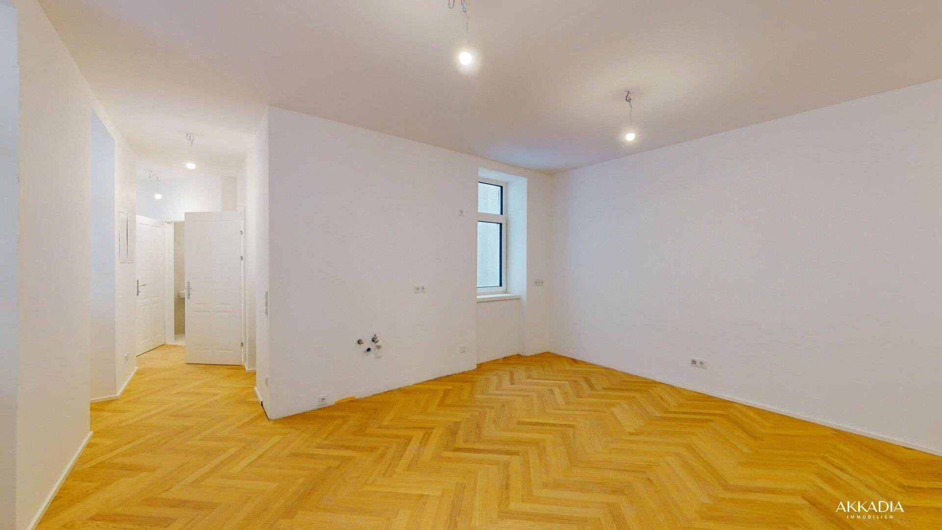 Heller, leerer Raum mit elegantem Fischgrätparkett und weißen Wänden, bereit zur Gestaltung.